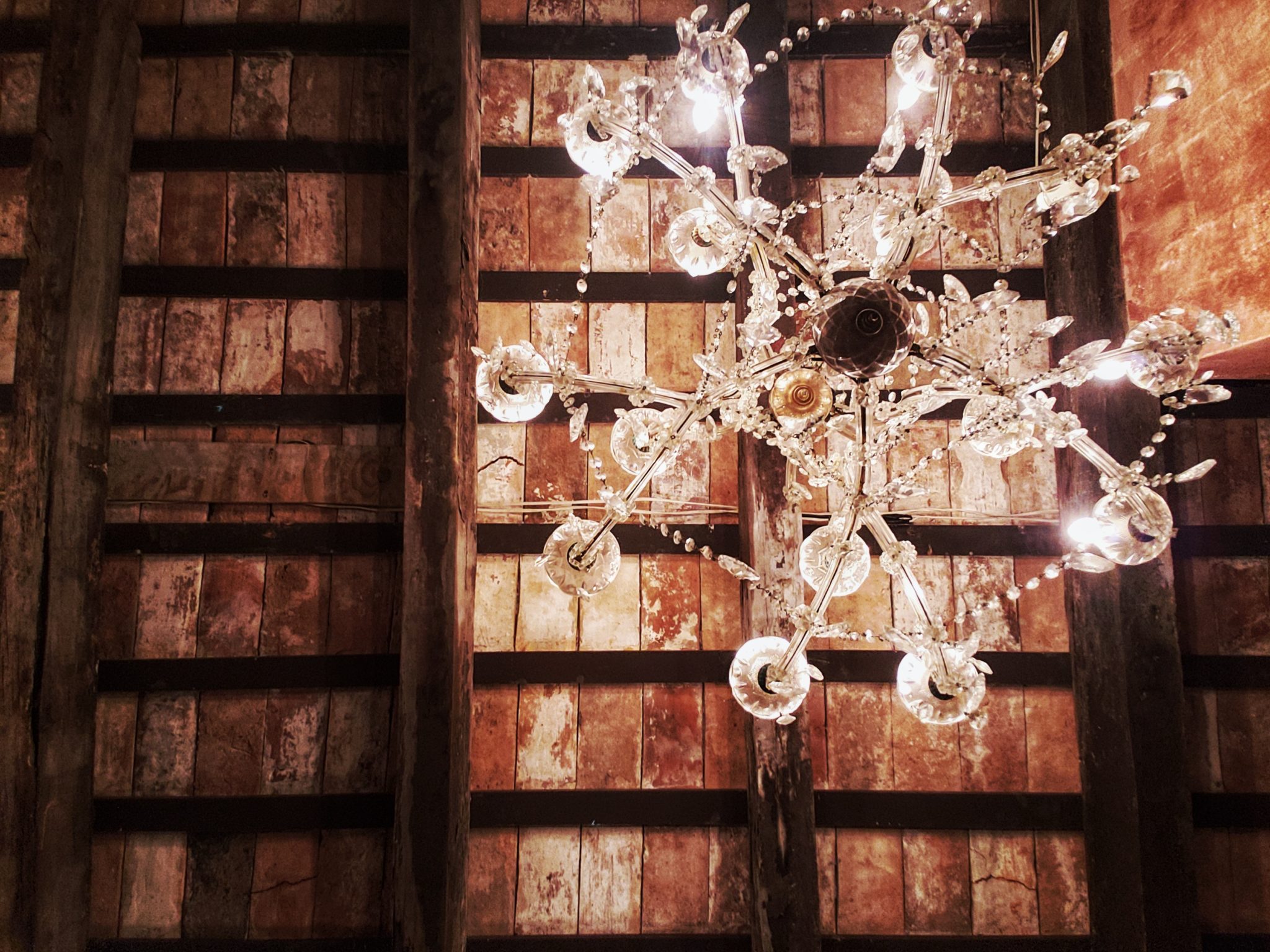 A crystal chandelier beneath weathered wooden beams