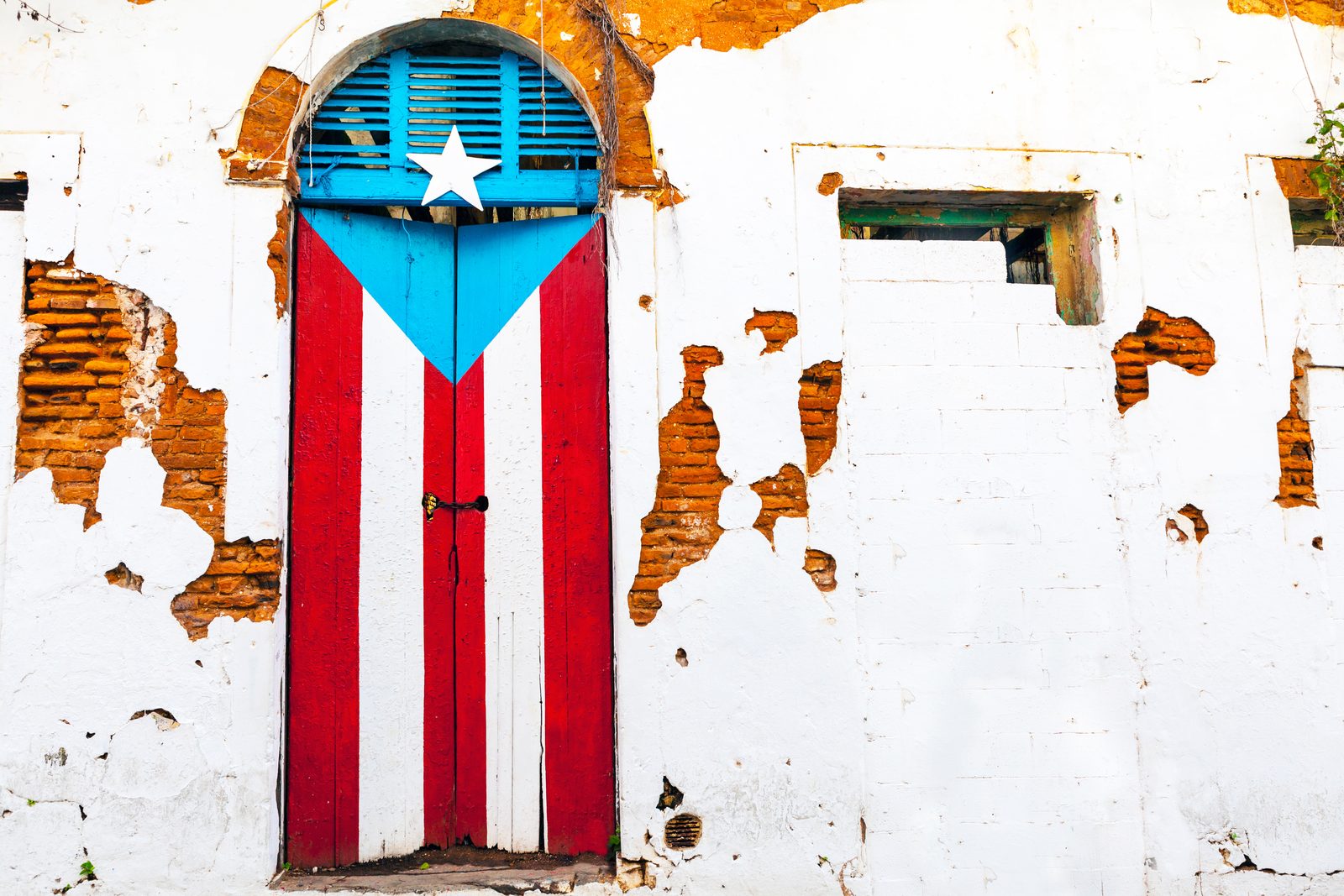 A weathered door painted with the Puerto Rican flag